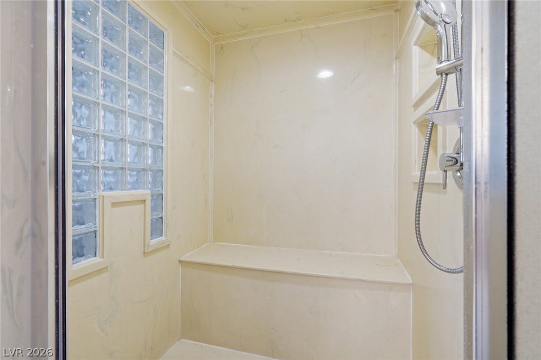 2212 Chatsworth Court, Henderson, NV 89074 Step into a spacious walk-in shower, featuring a built-in bench and light-filtering glass block window.