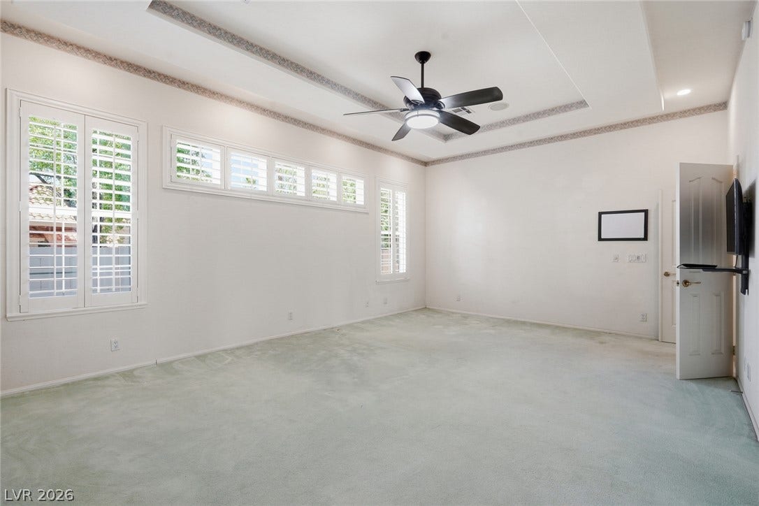 2212 Chatsworth Court, Henderson, NV 89074 A well-lit bedroom with plantation shutters, plush carpeting, and a stylish ceiling fan.