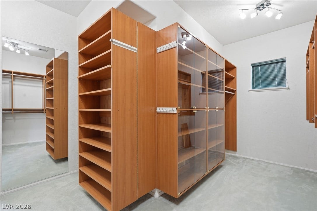 2212 Chatsworth Court, Henderson, NV 89074 Custom shelving and glass-fronted cabinetry create an organized walk-in closet.