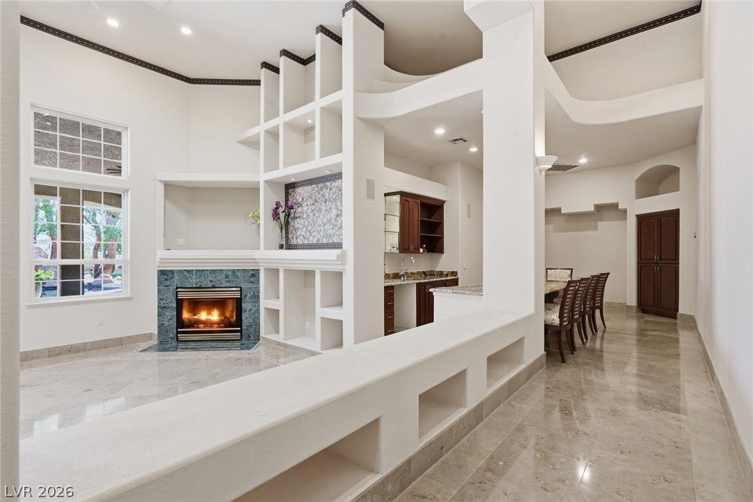 2212 Chatsworth Court, Henderson, NV 89074 A spacious living area with a fireplace, wet bar, and built-in shelving for modern living.
