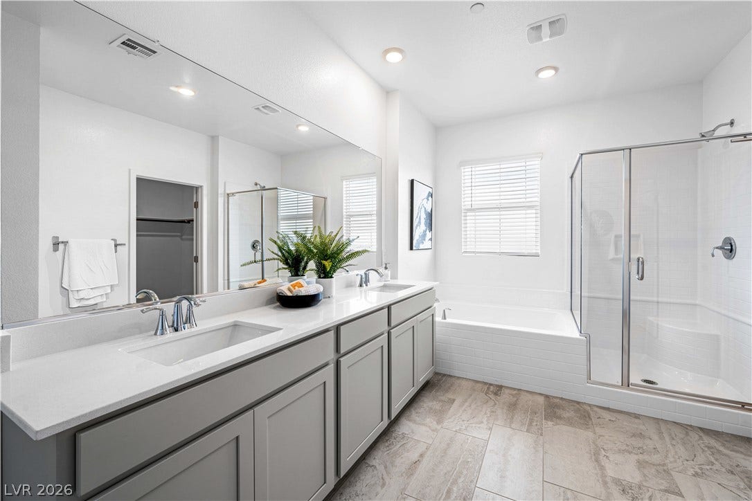132 Harper Crest Avenue, Henderson, NV 89011 An expansive double vanity sits on tile floors alongside a glass-enclosed shower and soaking tub.