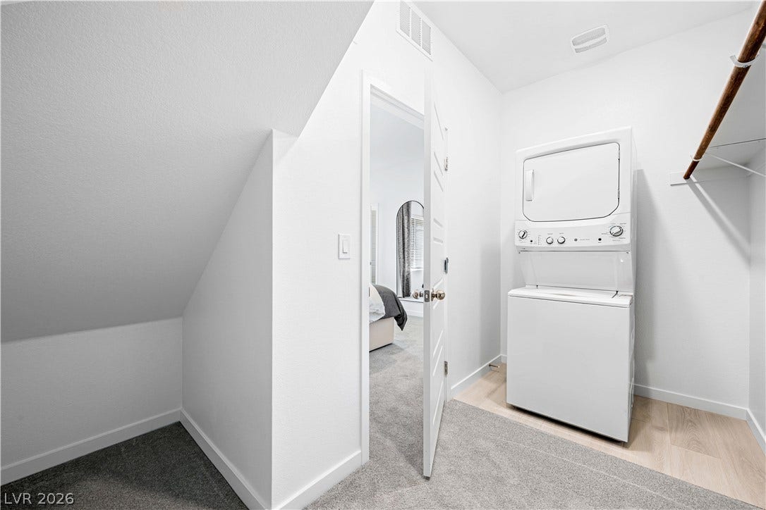 132 Harper Crest Avenue, Henderson, NV 89011 Functional laundry nook features wood-toned flooring and space-efficient stacked appliances.
