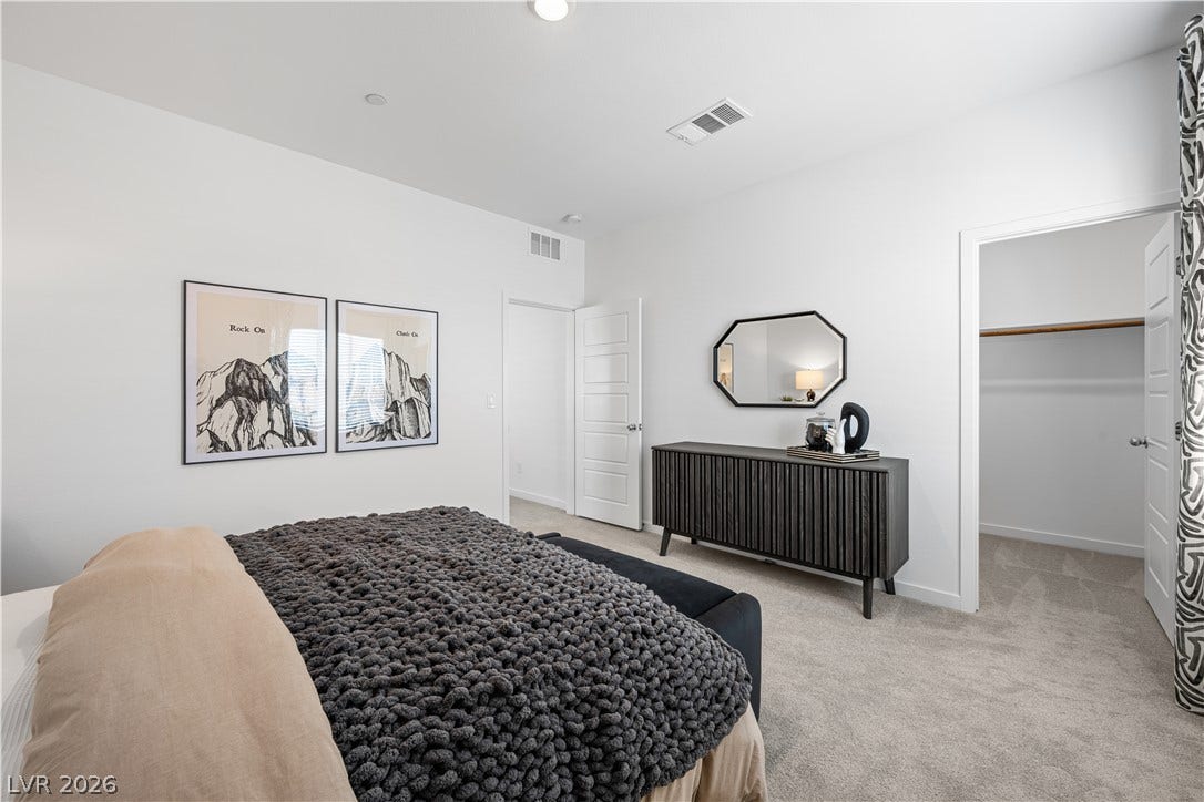 132 Harper Crest Avenue, Henderson, NV 89011 Plush carpet flooring and clean white walls anchor this bedroom featuring a walk-in closet.