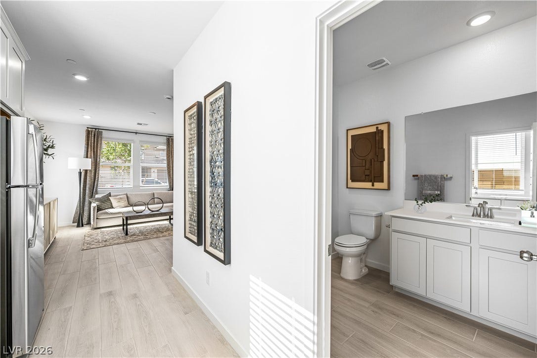 132 Harper Crest Avenue, Henderson, NV 89011 An open hallway with wood-look flooring leads past a bathroom into the living area.