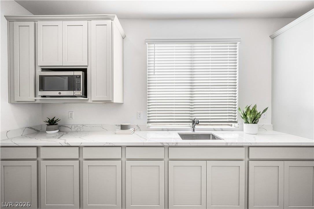 132 Harper Crest Avenue, Henderson, NV 89011 Elegant stone countertops and classic shaker cabinetry anchor this light-filled culinary space.