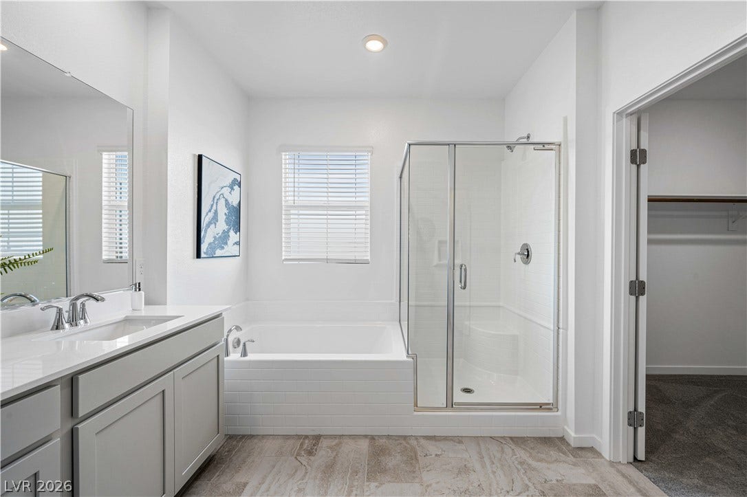 132 Harper Crest Avenue, Henderson, NV 89011 Tiled flooring pairs with a glass-enclosed shower and a soaking tub in this primary bathroom.
