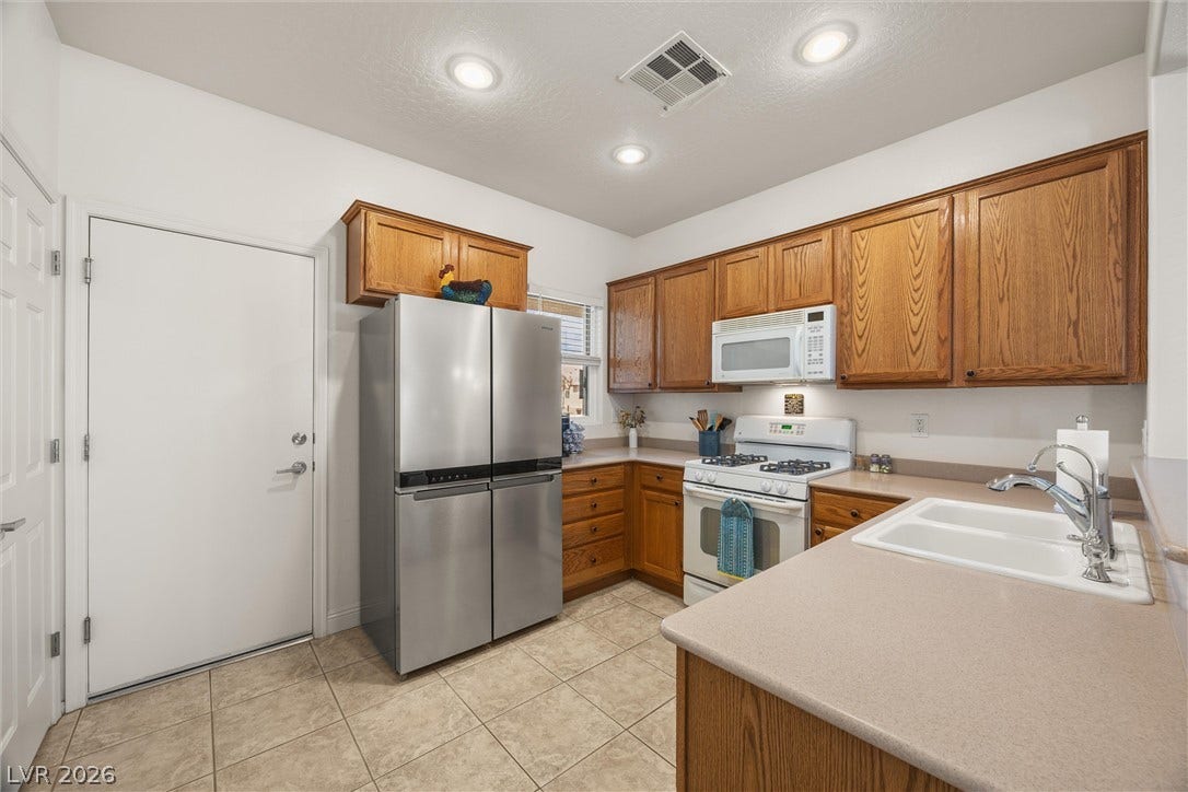 7940 Fantail Drive, North Las Vegas, NV 89084 Rich oak cabinetry pairs with clean tile flooring and classic white countertops in this kitchen.