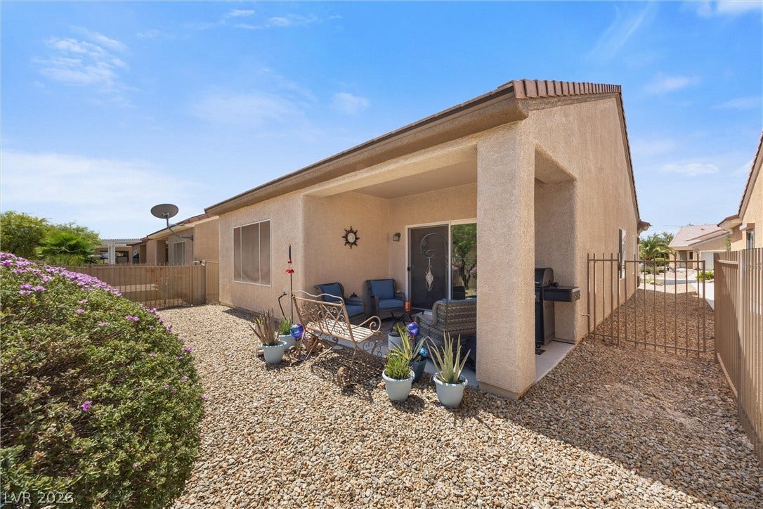 7940 Fantail Drive, North Las Vegas, NV 89084 A covered patio overlooks a gravel courtyard bordered by low fencing under clear blue skies.