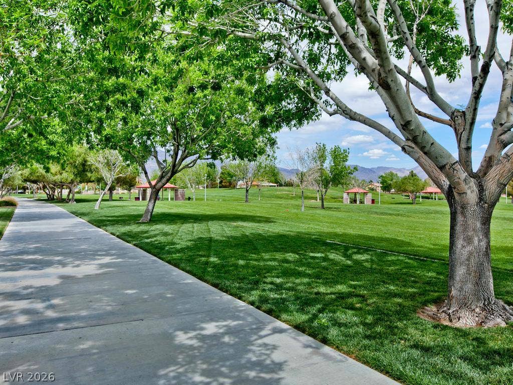 7940 Fantail Drive, North Las Vegas, NV 89084 Mature trees shade a wide paved pathway bordering a manicured community park.