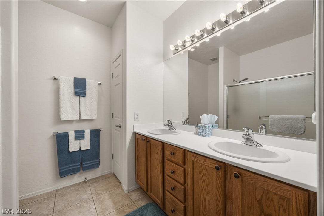 7940 Fantail Drive, North Las Vegas, NV 89084 Ample counter space and classic oak cabinetry define this functional primary bathroom layout.