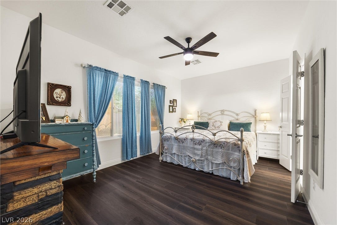 7940 Fantail Drive, North Las Vegas, NV 89084 Rich wood plank flooring and a classic stone fireplace surround anchor this comfortable bedroom.