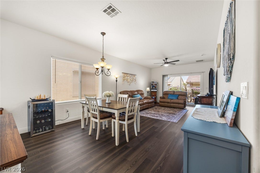 7940 Fantail Drive, North Las Vegas, NV 89084 Rich wood-look flooring anchors a modern dining space beneath a traditional chandelier.