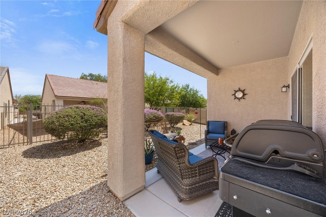 7940 Fantail Drive, North Las Vegas, NV 89084 A sheltered concrete patio borders a low-maintenance gravel yard enclosed by metal fencing.