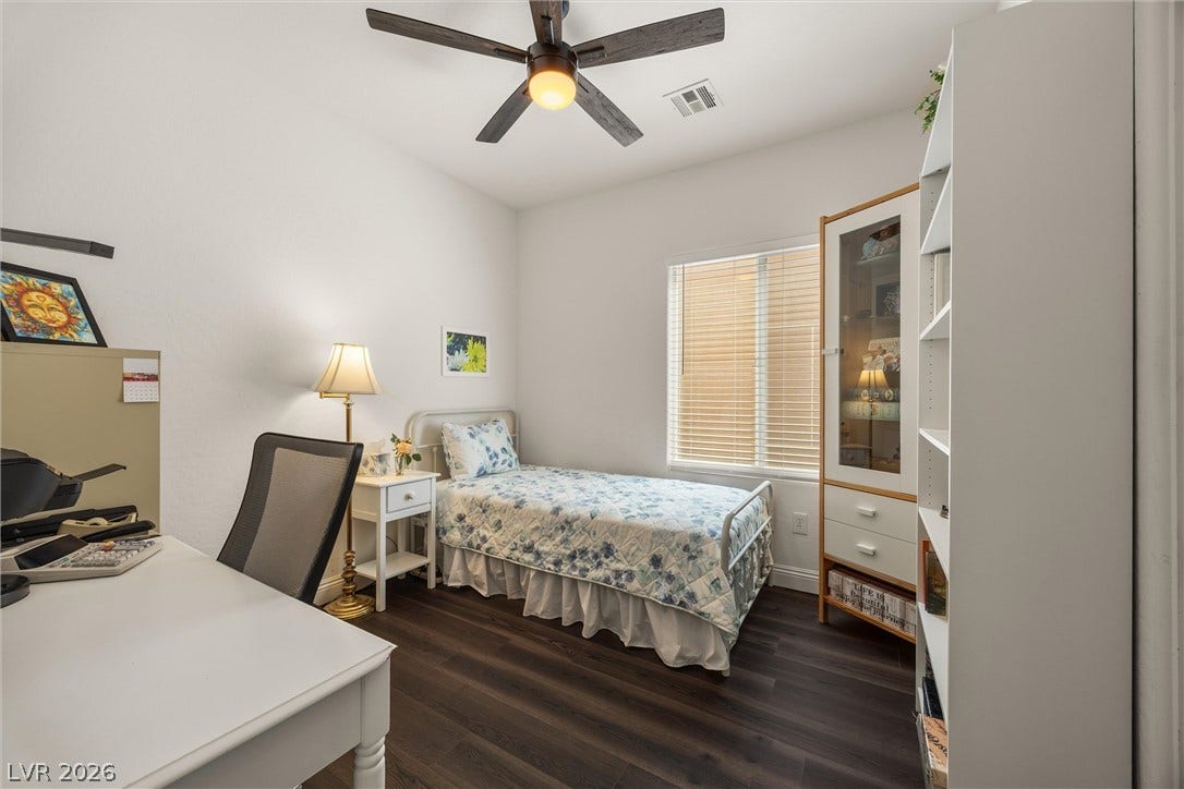 7940 Fantail Drive, North Las Vegas, NV 89084 Bedroom 3: Rich dark wood flooring anchors this comfortable guest suite complete with high ceilings and tall windows.