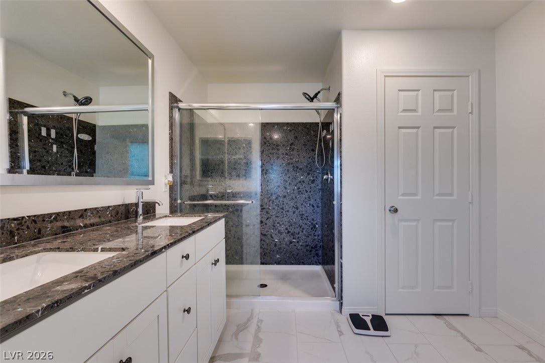 3231 Pergusa Drive, Henderson, NV 89044 Polished stone counters and matching shower surrounds anchor this modern bathroom design.