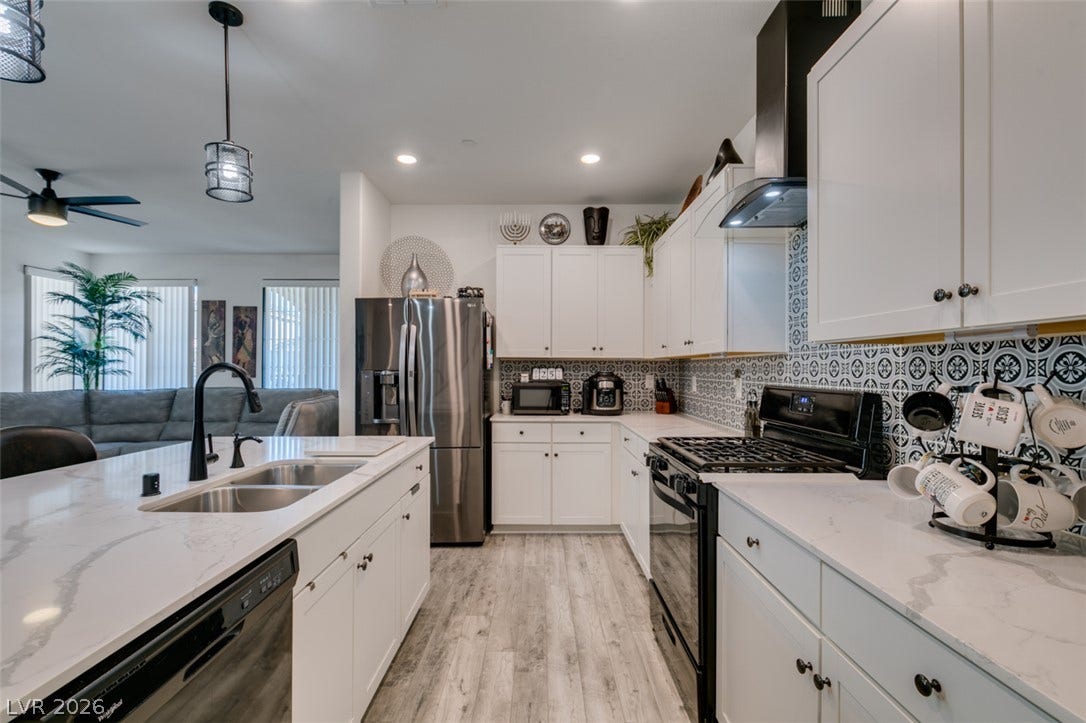 3231 Pergusa Drive, Henderson, NV 89044 An open kitchen boasts patterned tile backsplashes, custom countertops, and durable wood-look flooring.