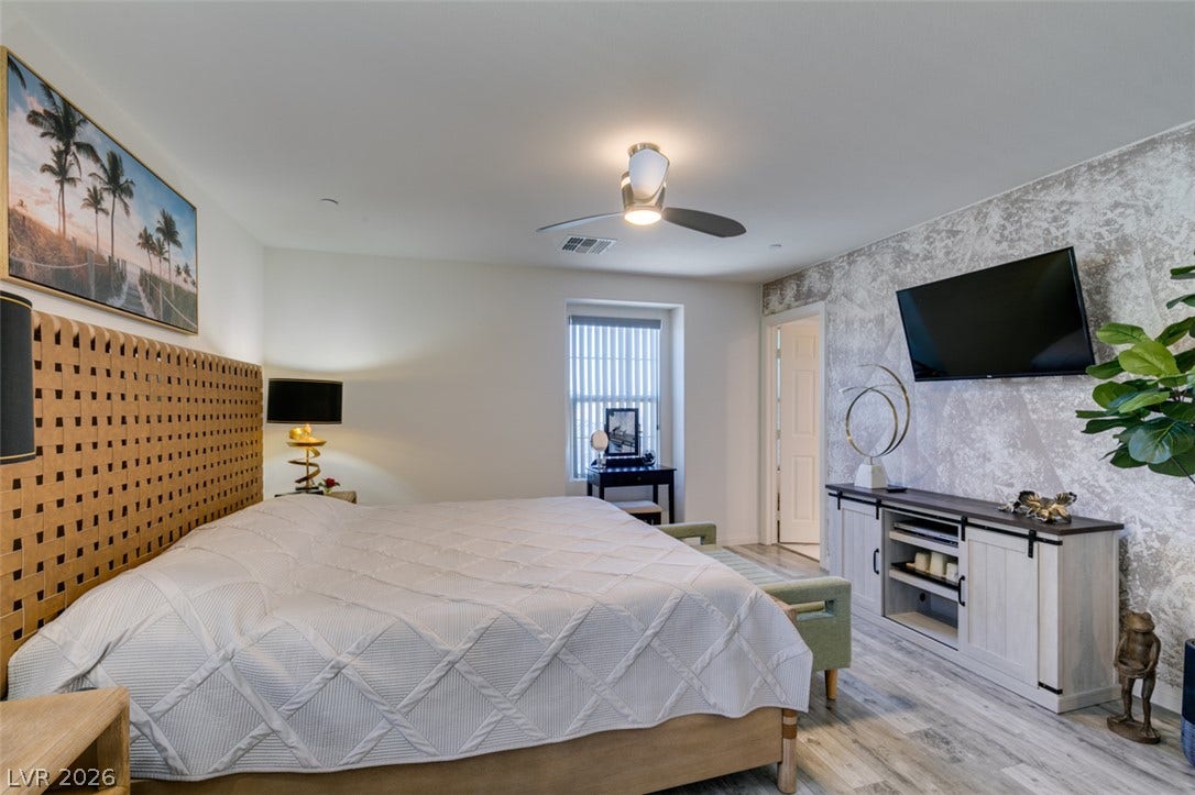 3231 Pergusa Drive, Henderson, NV 89044 Plank flooring and a textured feature wall define this comfortable main bedroom suite.