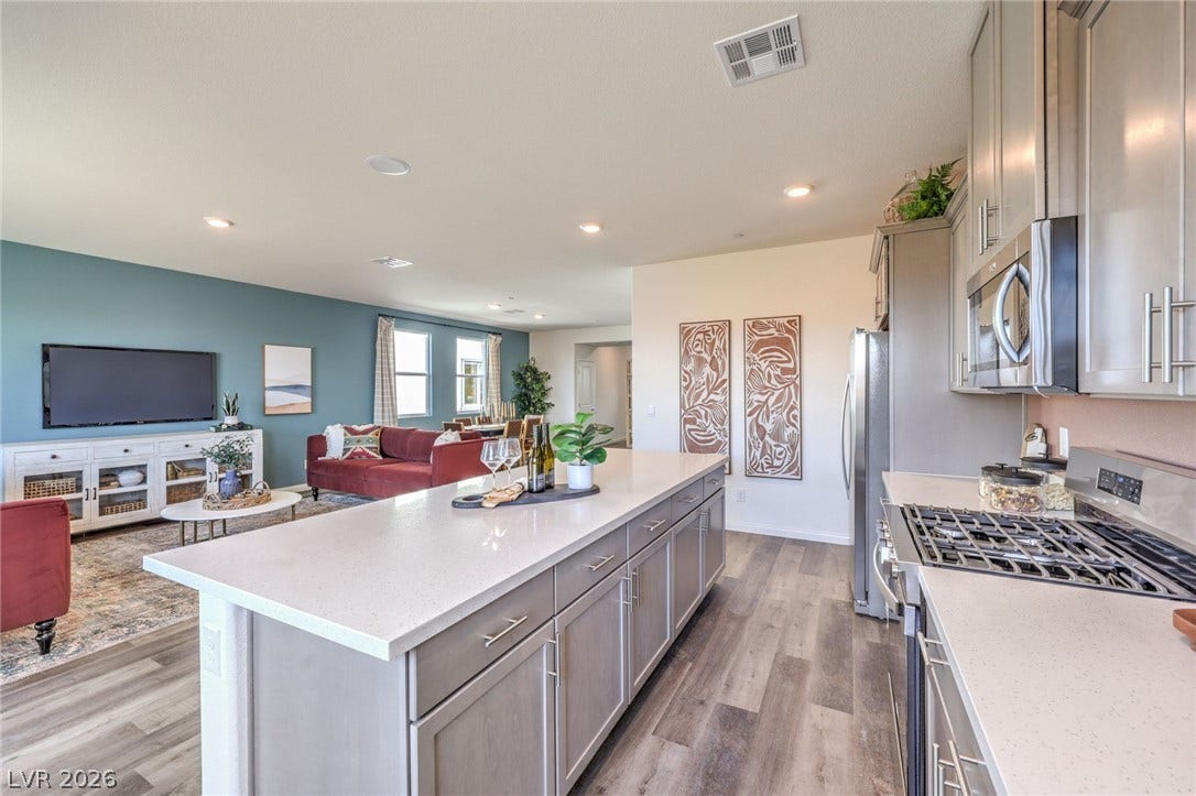 1036 PEACOCK PLUME Street, Henderson, NV 89011 Kitchen with stainless steel appliances, open floor plan, gray cabinets, light countertops, and light wood finished floors. Photo is representational only; actual home finishes may vary.
