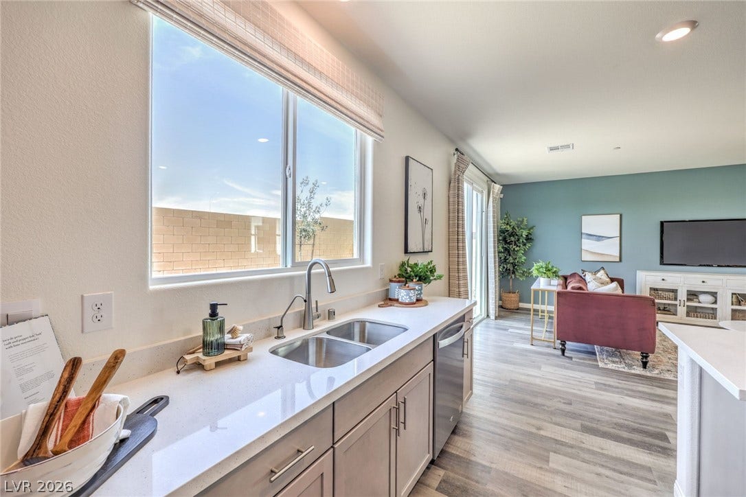 1036 PEACOCK PLUME Street, Henderson, NV 89011 Kitchen with a sink, stainless steel dishwasher, light countertops, light. wood-type flooring, and open floor plan. Photo is representational only; actual home finishes may vary.