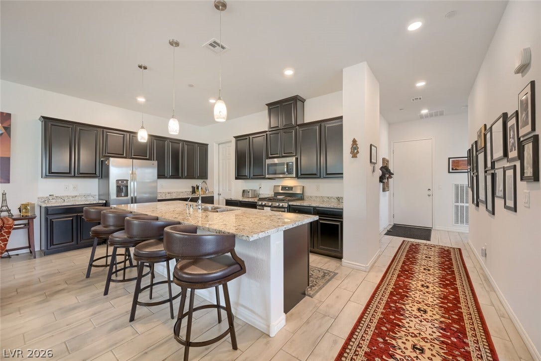 747 Orange Plume Walk, Henderson, NV 89011 Dark cabinetry and granite countertops create a striking contrast on light wood-look flooring.