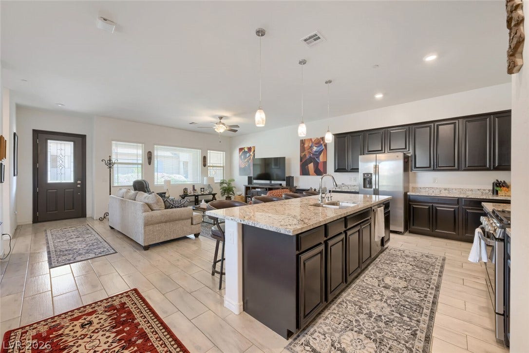 747 Orange Plume Walk, Henderson, NV 89011 Granite countertops and dark cabinetry anchor this open-concept kitchen and living area.