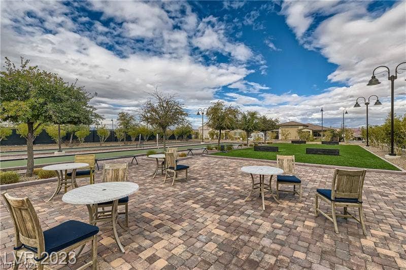 747 Orange Plume Walk, Henderson, NV 89011 An inviting stone paver patio offers a serene community park setting under blue skies.