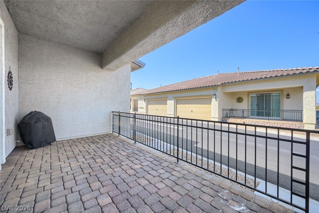 747 Orange Plume Walk, Henderson, NV 89011 A covered patio featuring interlocking stone pavers and a secure wrought iron railing overlooks the neighborhood.