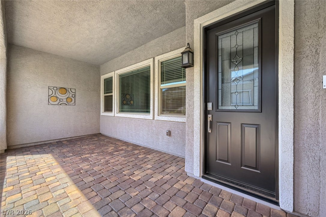 747 Orange Plume Walk, Henderson, NV 89011 An inviting covered entryway showcases a decorative glass front door and paved brick flooring.