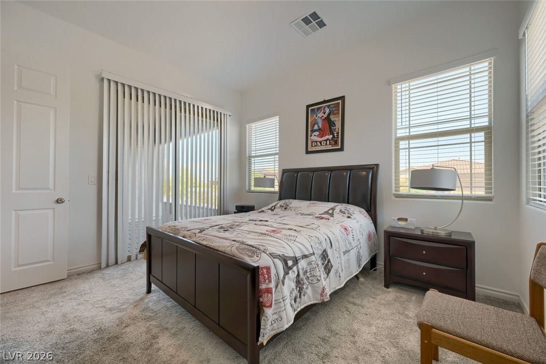 747 Orange Plume Walk, Henderson, NV 89011 Plentiful windows fill this carpeted bedroom with natural light through tall glass sliding doors.