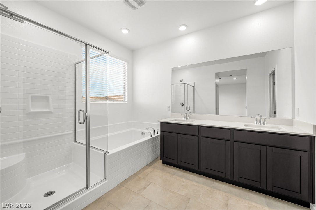 An elegant tile floor runs through this bathroom featuring a dual vanity and separate soaking tub.