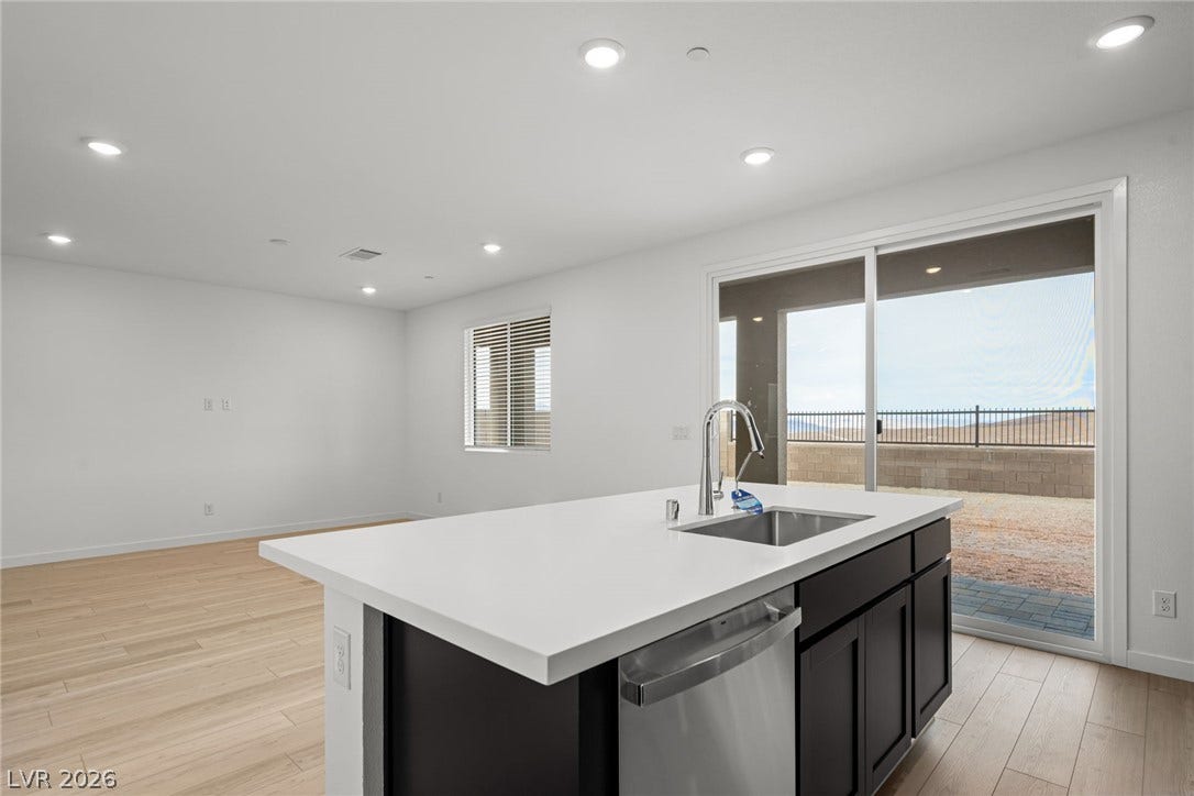 An open floor plan connects the kitchen island to sliding glass doors and wood flooring.