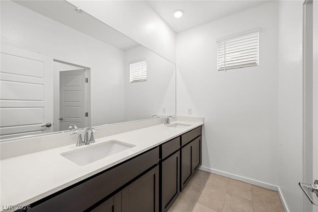 An expansive double vanity with stone counters anchors this modern bathroom space.