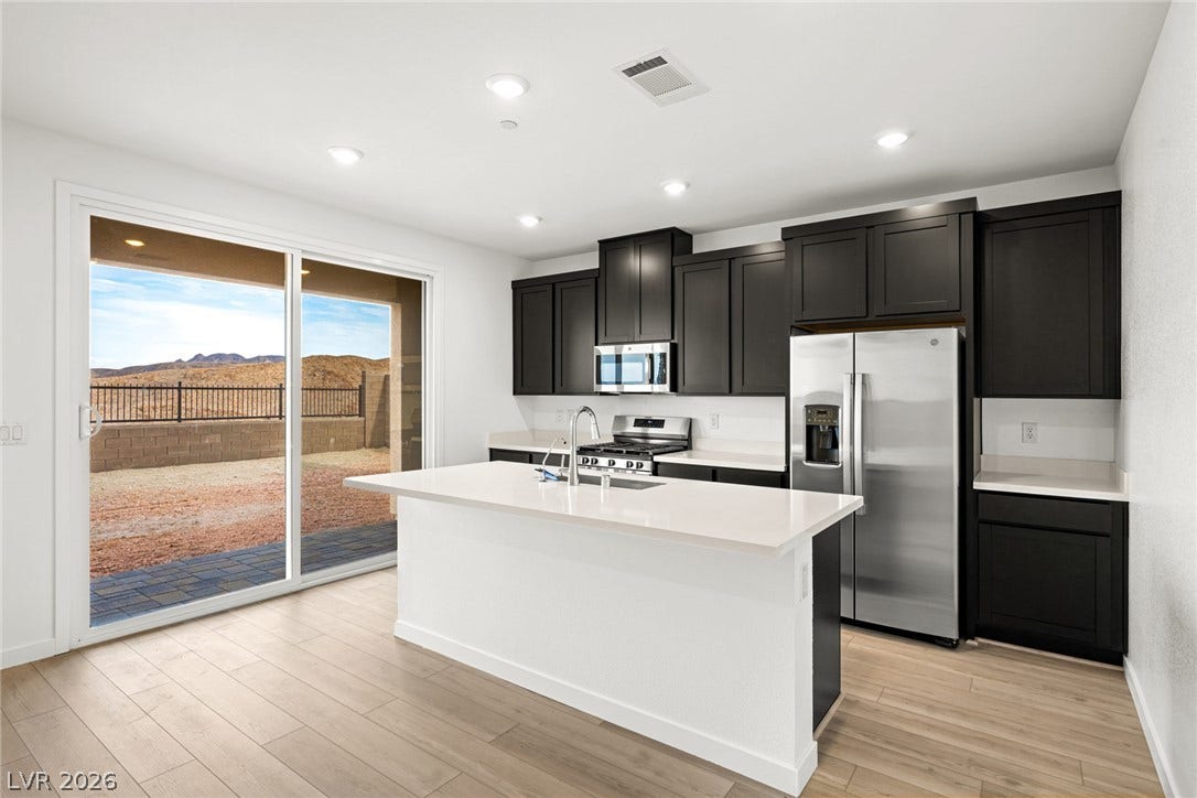 Sliding glass doors open from the kitchen to reveal expansive desert mountain views.