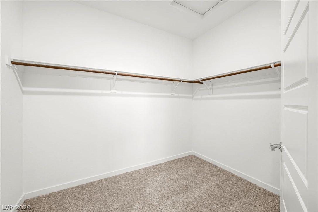 Ample hanging space highlights this clean walk-in closet finished with soft carpeting.