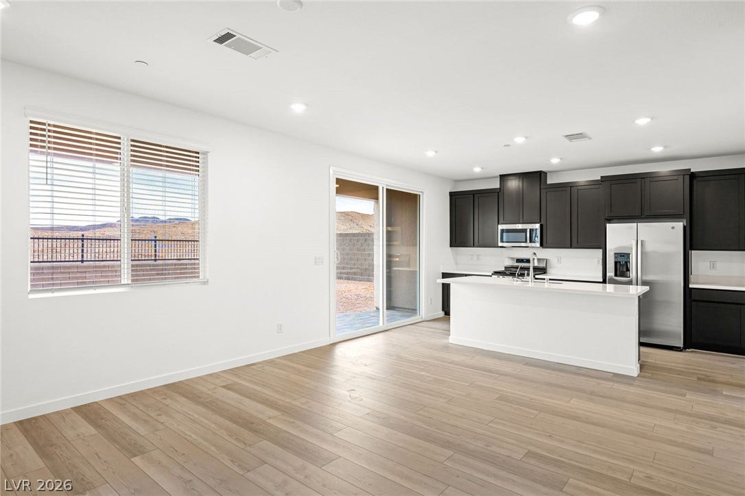 Clean lines and warm plank flooring define this airy open-concept kitchen and living area.