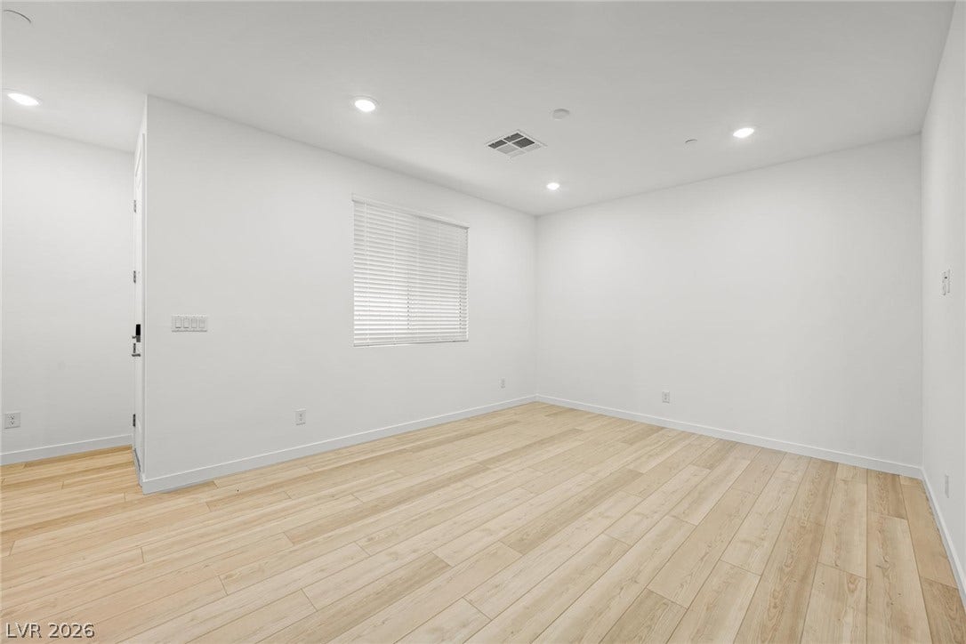 Recessed lighting and wide-plank wood-style floors elevate this versatile, sunlit interior space.