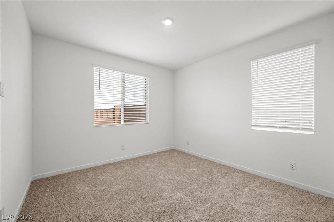 Plush carpeting and dual windows enhance this clean, versatile bedroom space.