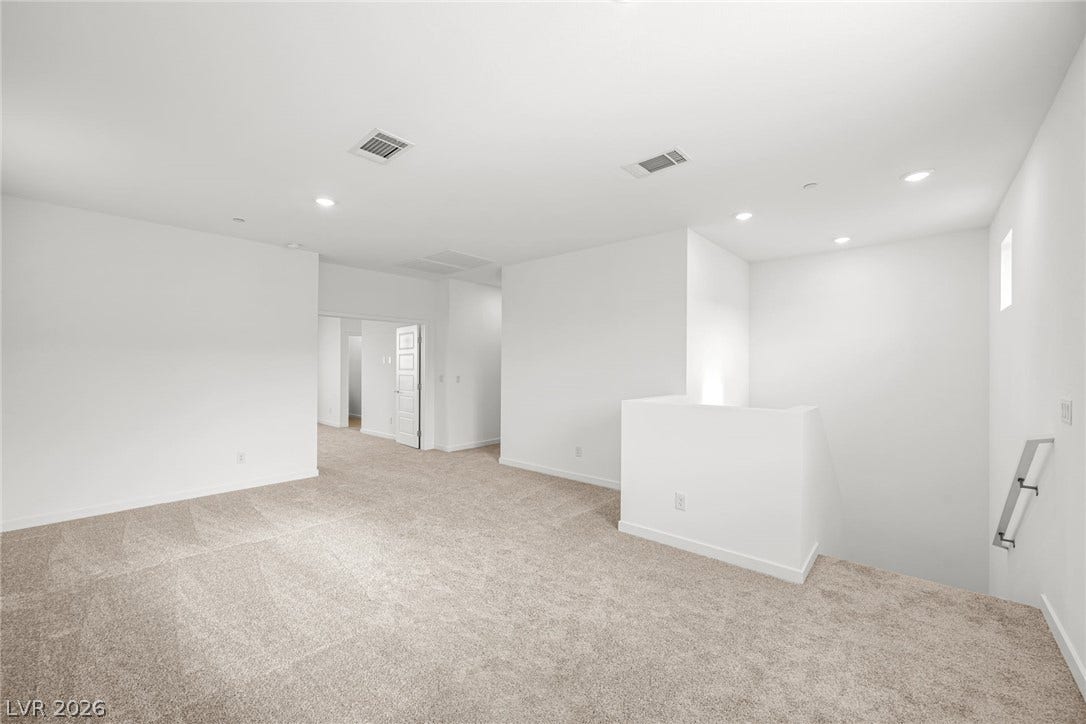 Plush carpeting and crisp white walls define this versatile upper-level loft space.