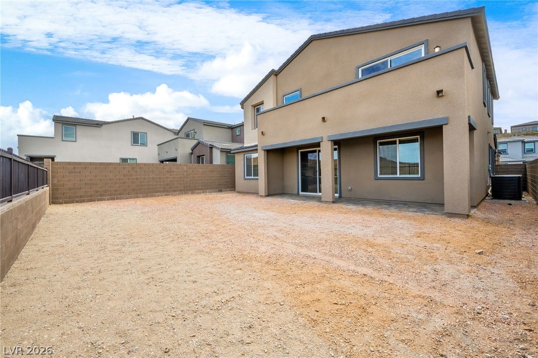 An enclosed backyard area features a covered patio and sturdy block wall fencing.