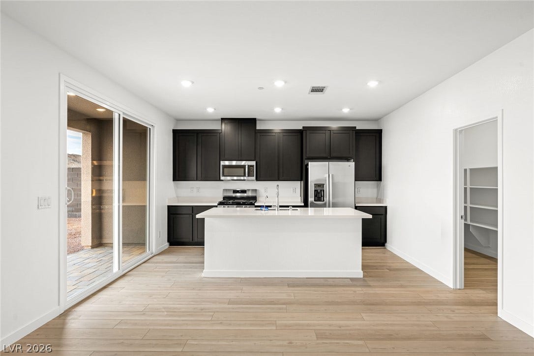 Sliding glass doors open to the patio from this modern culinary space.