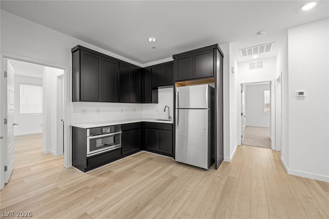 Crisp white walls contrast with dark cabinetry and light wood flooring in this modern kitchen.