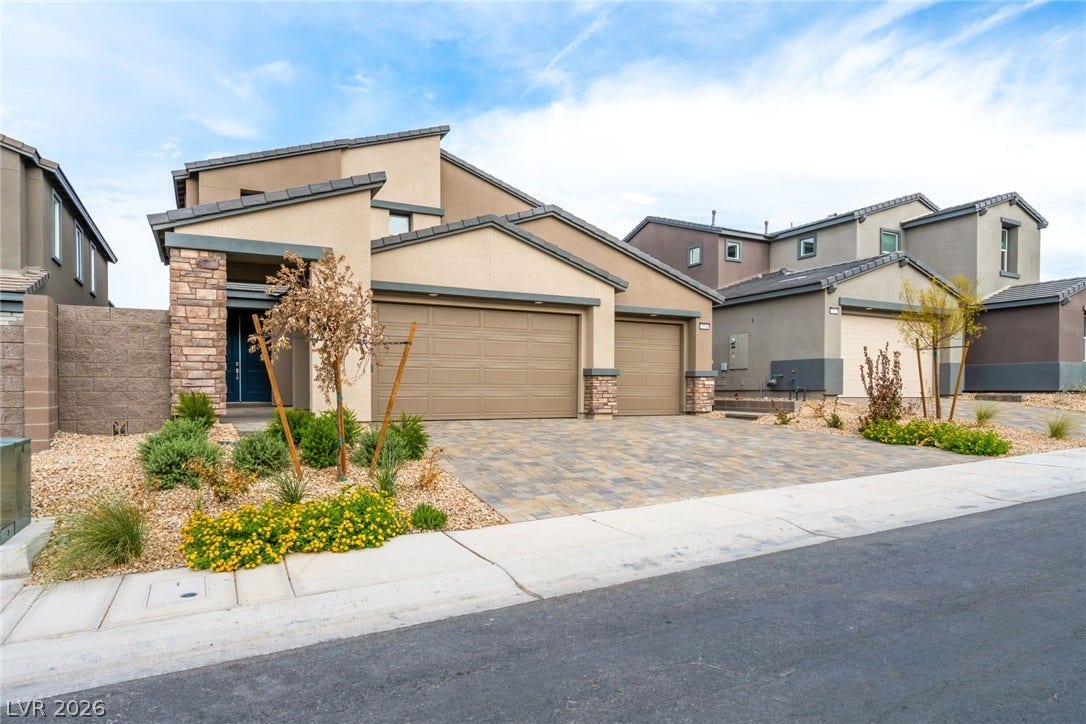Modern architecture pairs with stone accents and a paved driveway under wide desert skies.