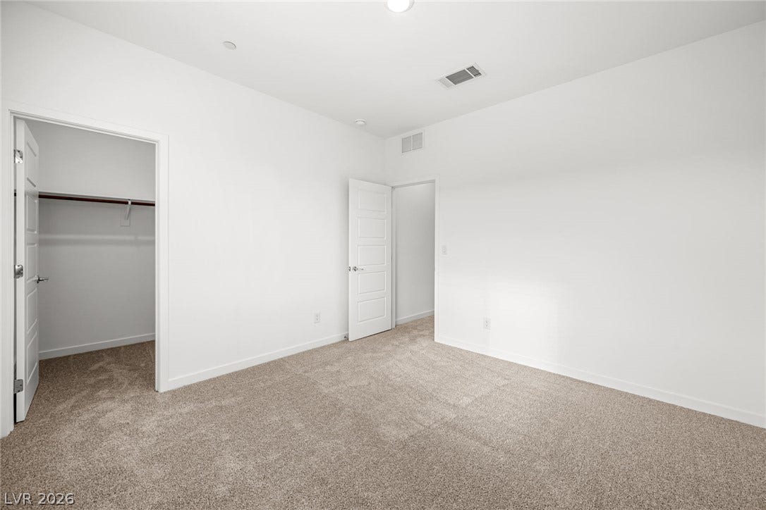 Plush carpeting anchors this bright bedroom with a spacious walk-in closet.
