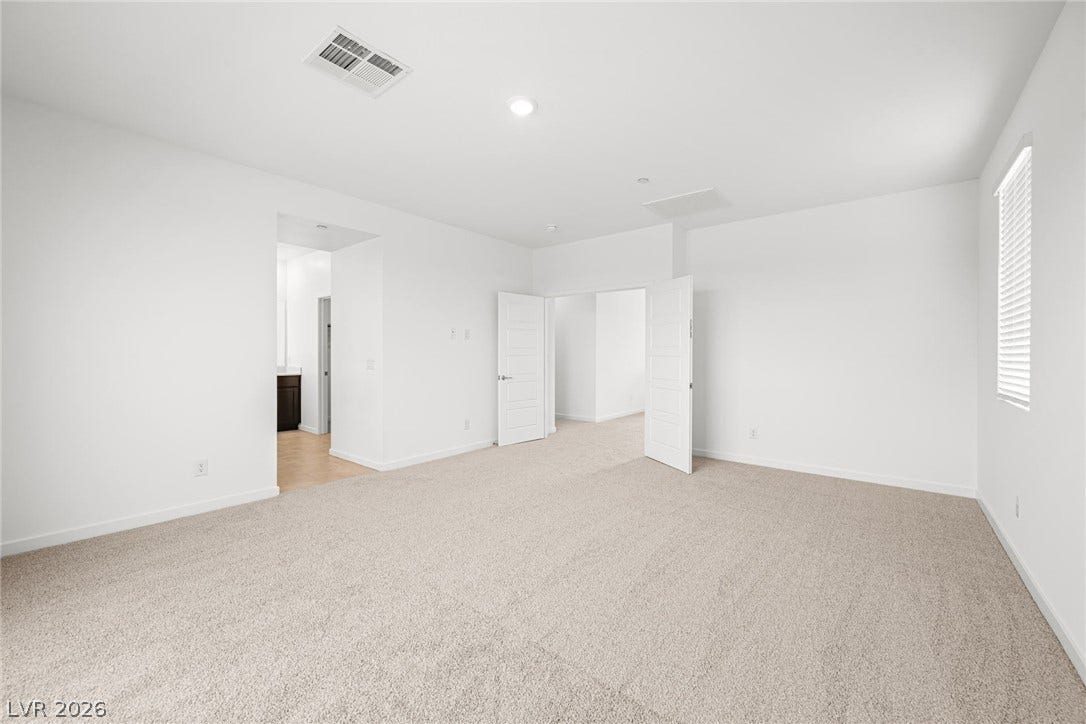 Plush carpeting and crisp white walls define this airy, light-filled bedroom suite.