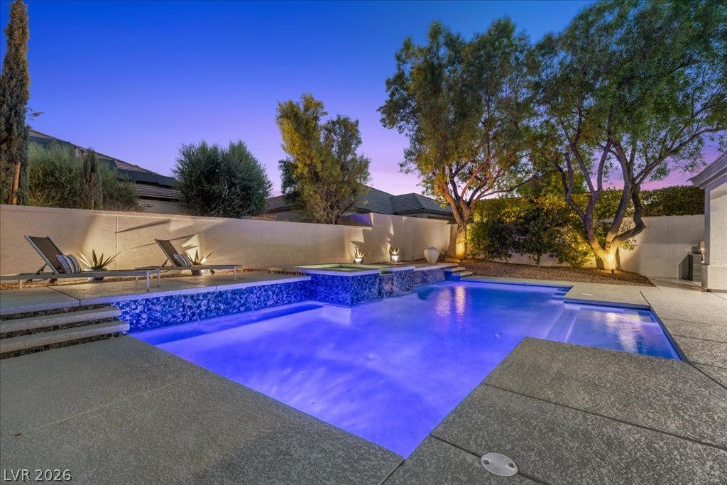9425 Garnet Crown Avenue, Las Vegas, NV 89145 Lush landscaping and stone decking frame a sparkling swimming pool under evening skies.