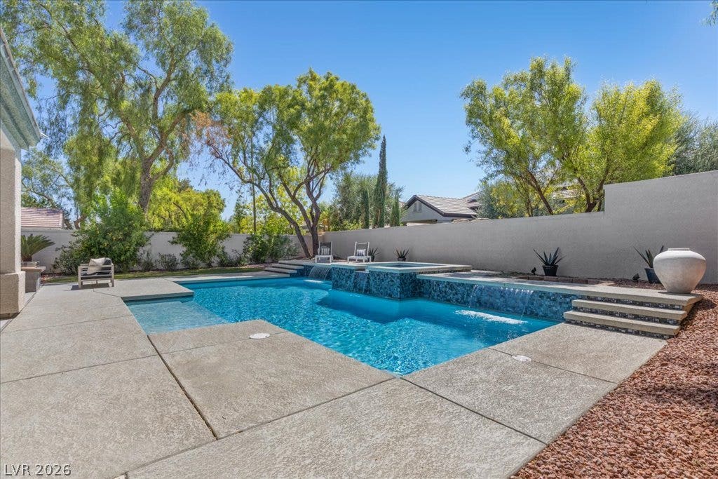 9425 Garnet Crown Avenue, Las Vegas, NV 89145 Lush mature trees frame a sparkling swimming pool and integrated spa surrounded by concrete decking.