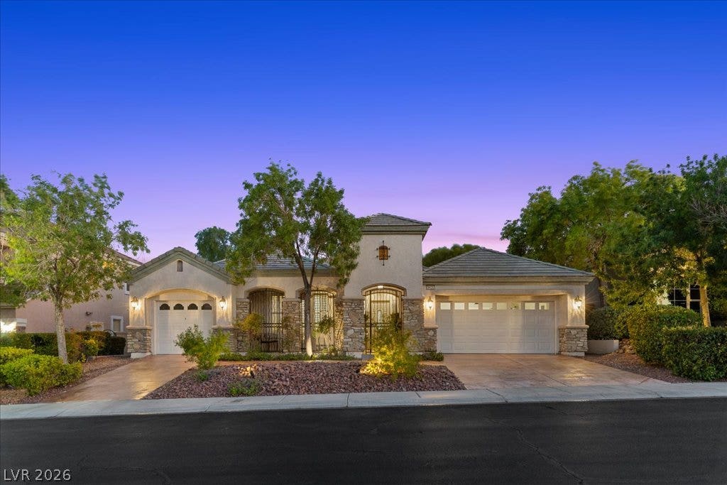 9425 Garnet Crown Avenue, Las Vegas, NV 89145 Striking stone accents and a manicured landscape frame this classic single-story home at twilight.