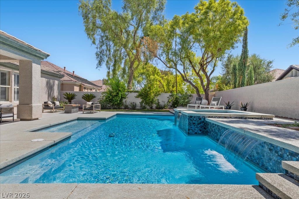 9425 Garnet Crown Avenue, Las Vegas, NV 89145 Mature trees frame a private swimming pool complete with a built-in spa and cascading waterfall features.