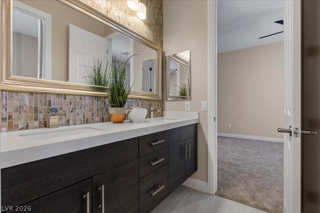 9425 Garnet Crown Avenue, Las Vegas, NV 89145 Stone counters and a tiled backsplash elevate this elegant dual vanity bathroom setup.