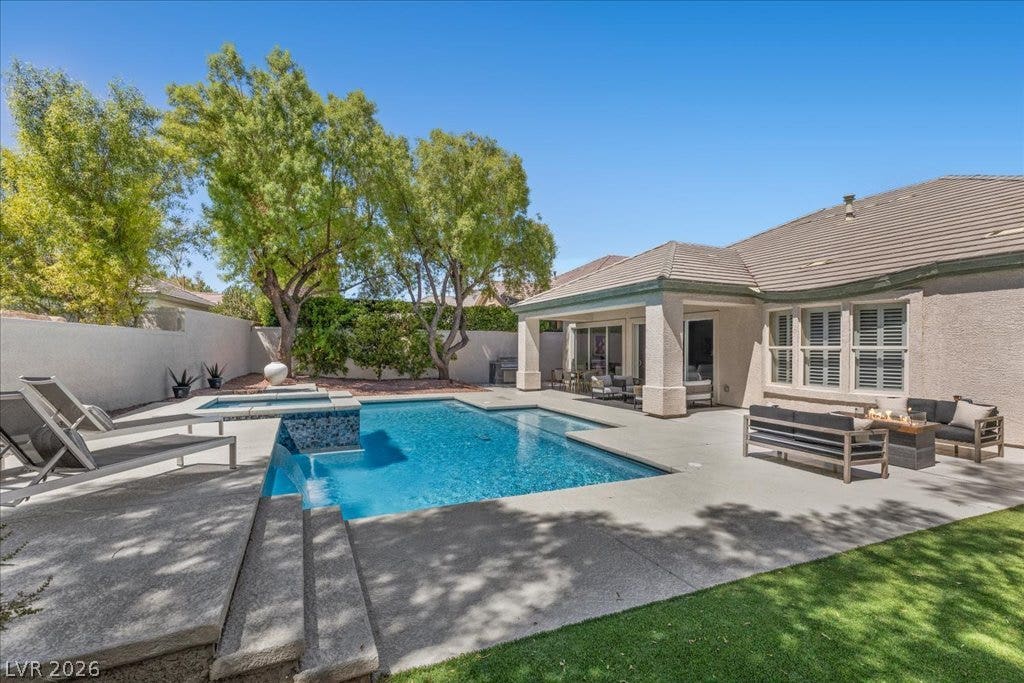 9425 Garnet Crown Avenue, Las Vegas, NV 89145 Mature trees frame a private backyard oasis featuring a geometric pool, spa, and covered patio.